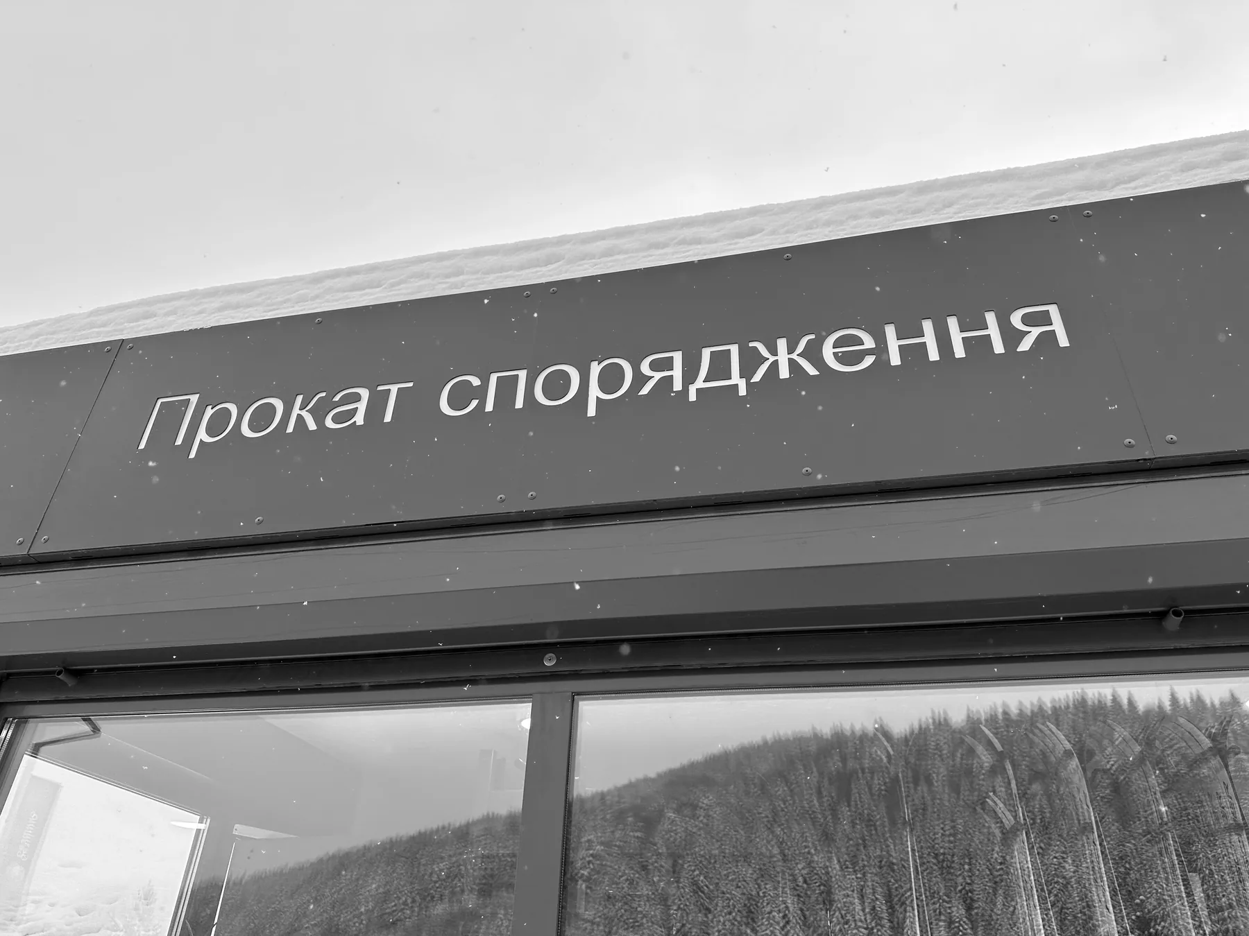 Sign reading Prokat sporyadzhennya, equipment rental, above the window of a Bukovel rental point