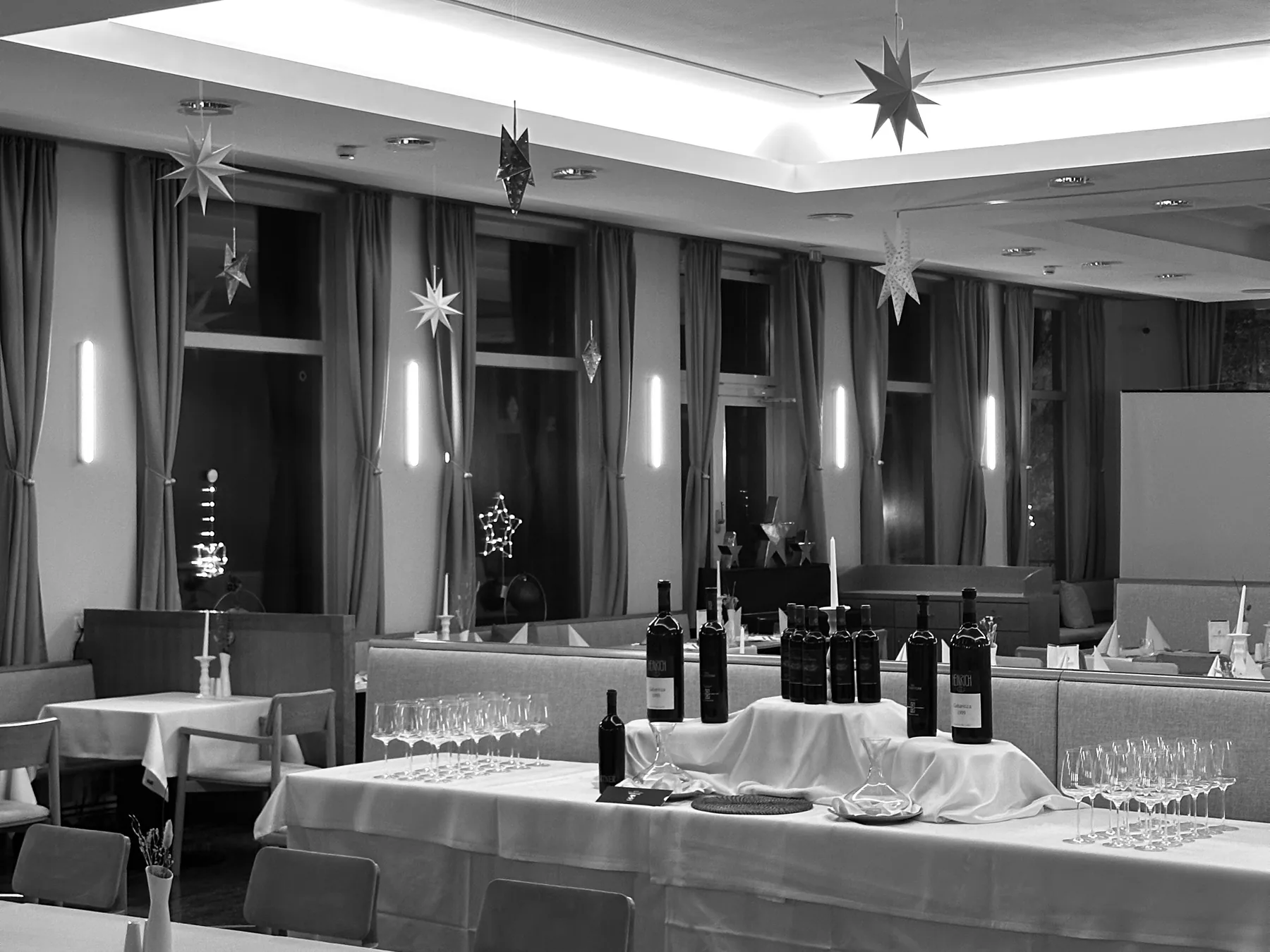 The restaurant set for December: white tablecloths, wine bottles, paper stars in the windows